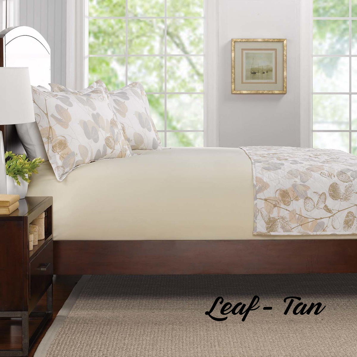 A neatly made bed features WestPoint Home's Comforters - WestPoint Hospitality - Pattern in tan and white leaf print, recalling hotel bedding, set in a bright room with windows, books on a nightstand, and "Leaf - Tan" text at lower right.