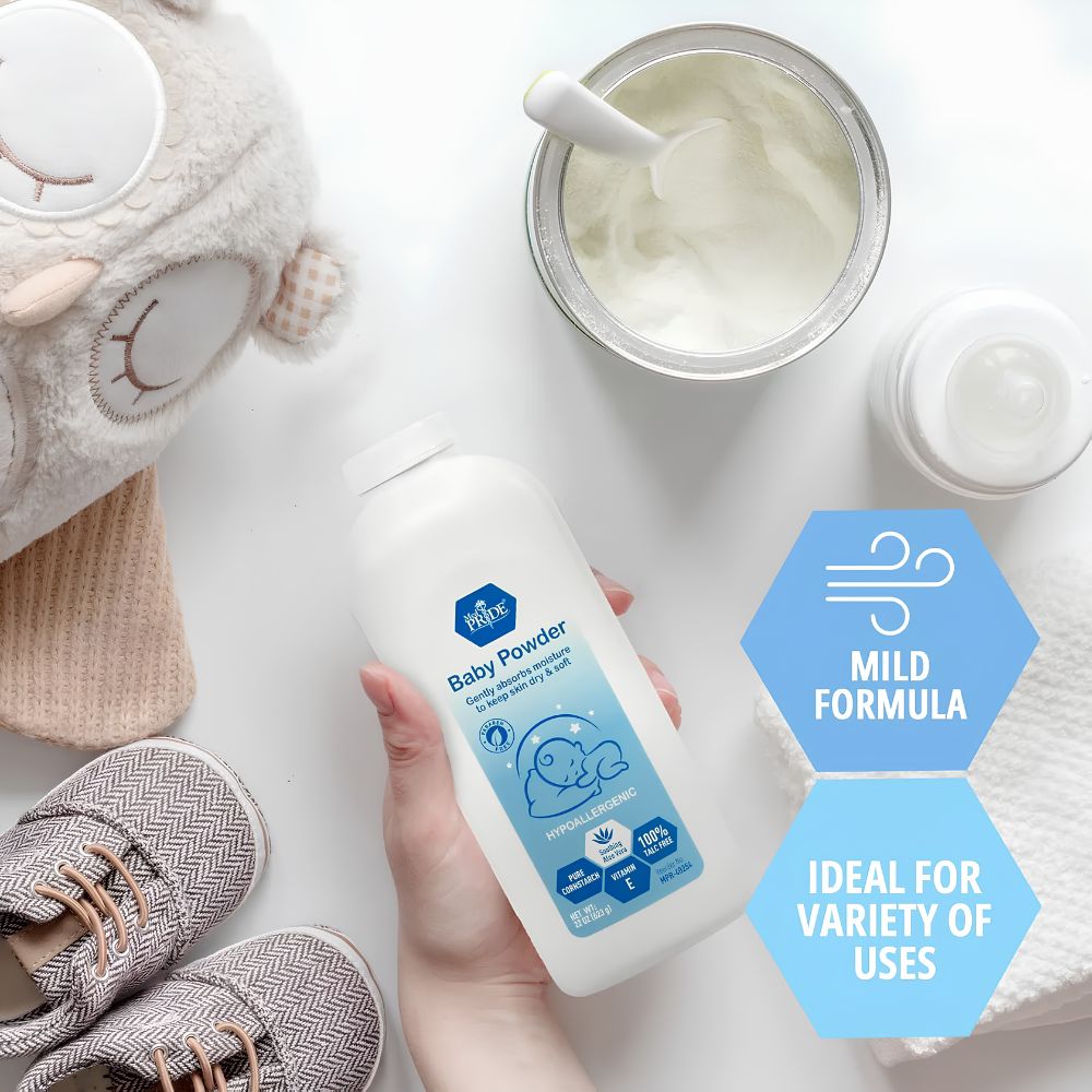 A hand holds a Shield Line MedPride Baby Powder w/seal (22 oz, white bottle) on a white surface, with a stuffed owl, small shoes, towel, baby bottle, and bowl of powder. Mild formula offers moisture protection for delicate skin and various uses.