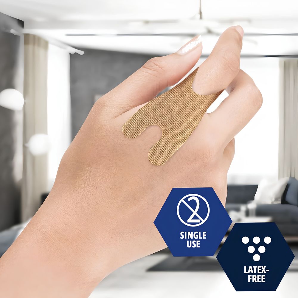 A hand with a beige Shield Line MedPride Sterile Fabric Knuckle Adhesive Bandage (1.5" x 3") on the thumb and back of the hand. Overlay text notes Single Use and Latex-Free. The background features a modern living room.