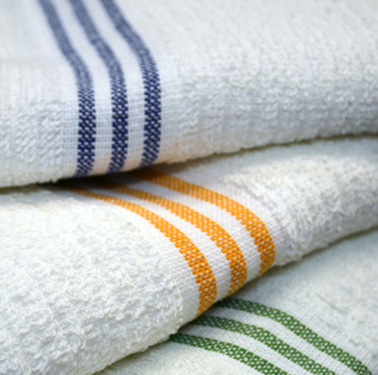 Three White Oxford Three Stripes Pool Towels from Ganesh Mills are stacked, each featuring blue, gold, and green stripes near the edge—perfect for anyone needing bulk pool towels.