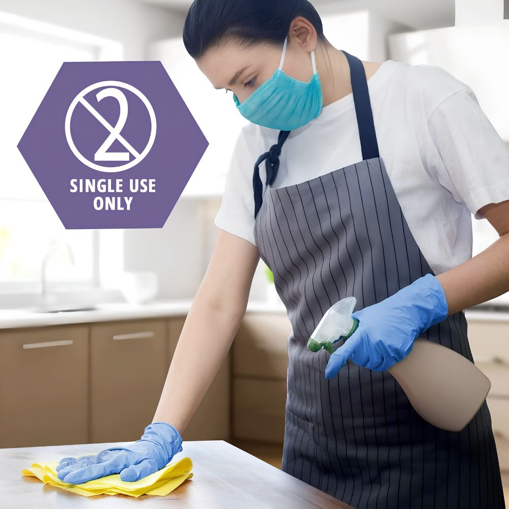Wearing Shield Line MedPride Synthetic Vinyl Exam Gloves, a person cleans a kitchen counter with a spray bottle and cloth. A “Single Use Only” symbol appears beside them, highlighting the gloves’ non-sterile, powder-free design.