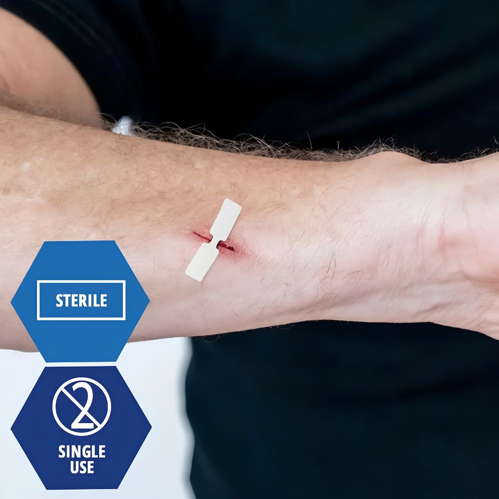 A close-up of a forearm with a small cut secured by Shield Line MedPride Butterfly Wound Closures Fabric Bandage (Medium: 3/8" x 1 13/16", Large: 1/2" x 2.75"), sterile and single use, set against a dark background.