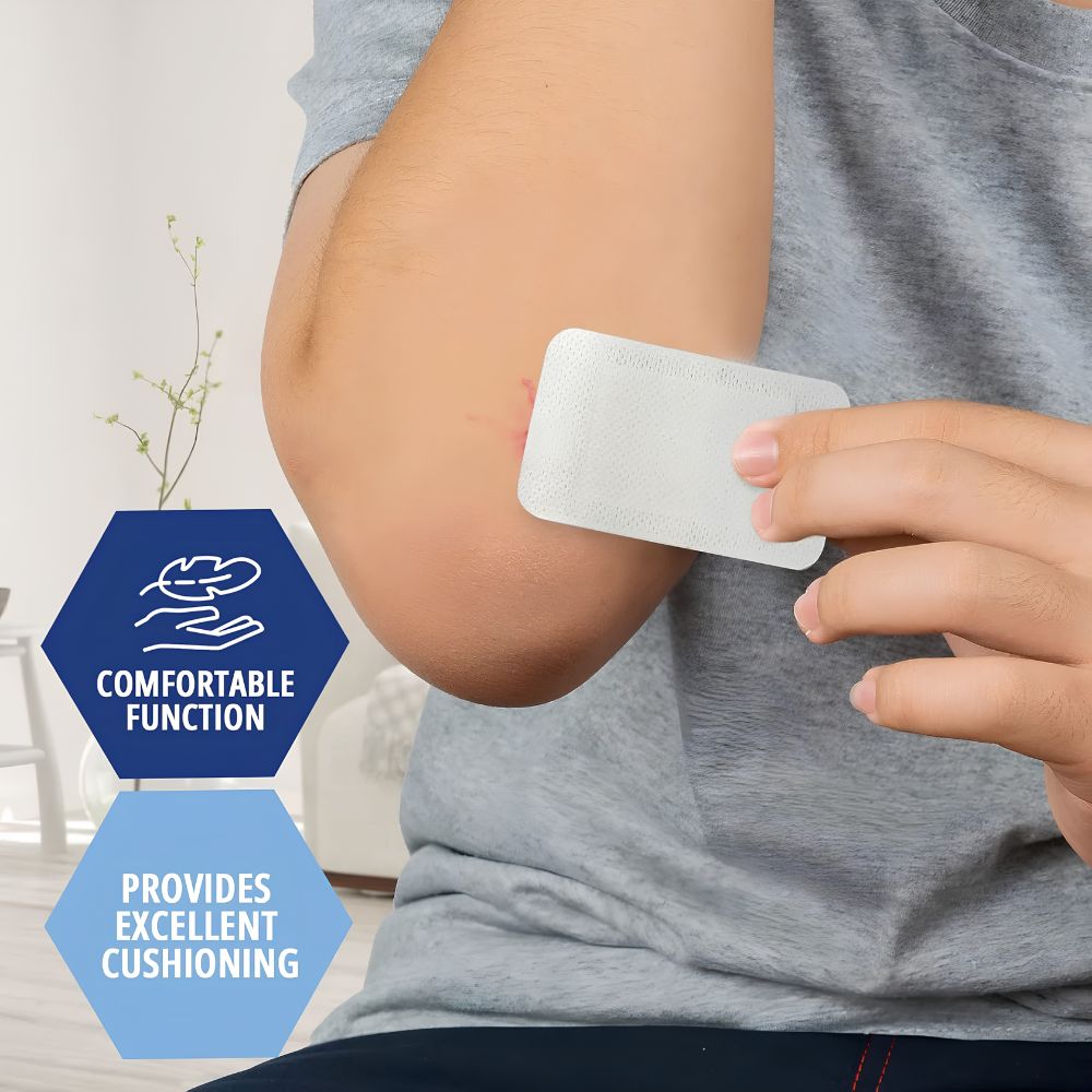 A person in a grey shirt applies Shield Line Medpride Gauze Island Dressing (2"x3.5", 4”x4", 6”x6”, 6”x8”) with adhesive to their elbow. Text on the image: Comfortable Function and Provides Excellent Cushioning.
