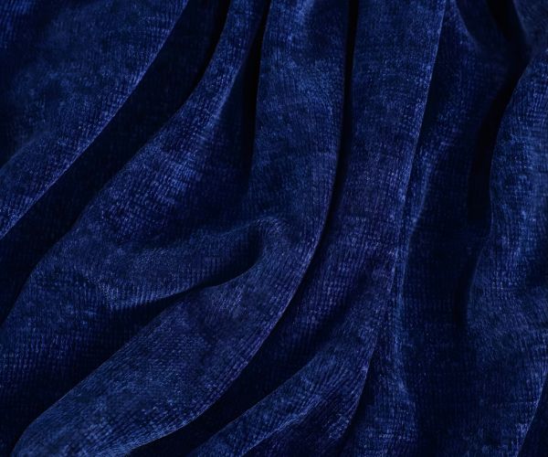 Rich, deep blue chenille fabric with a soft, plush texture is arranged in gentle folds, creating a luxurious look—perfect for the WestPoint Home Vellux Renew Chenille Blanket, reminiscent of a cozy hotel stay.