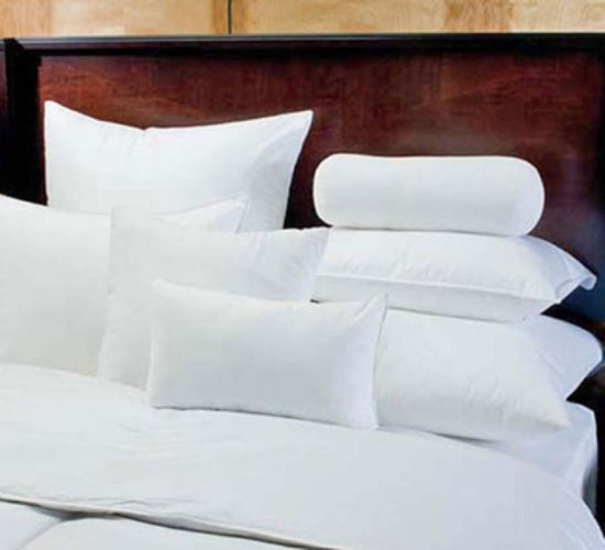 A neatly made bed features multiple white pillows of various shapes and sizes, each encased in a crisp Calderon Textiles Oxford Envelope Style Pillow Protector, arranged against a dark wooden headboard.