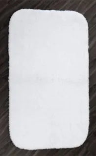 A rectangular, white, fluffy Bath Rug Rug-terry by 1Concier with rounded corners and latex backing from the 1Concier brand is placed on a dark wood floor.