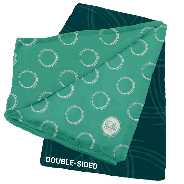 The Pro Vision Plush Throw by Pro Towels is a double-sided custom blanket with one dark green side of subtle circles and a lighter green side with bold white rings plus a Firefly logo—an ideal personalized gift.