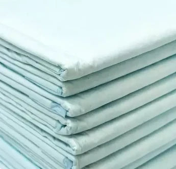 A close-up view of neatly stacked Oxford Hospital Bed Pads in green and pink by Ganesh Mills, ideal as reusable bed pads for added incontinence protection.