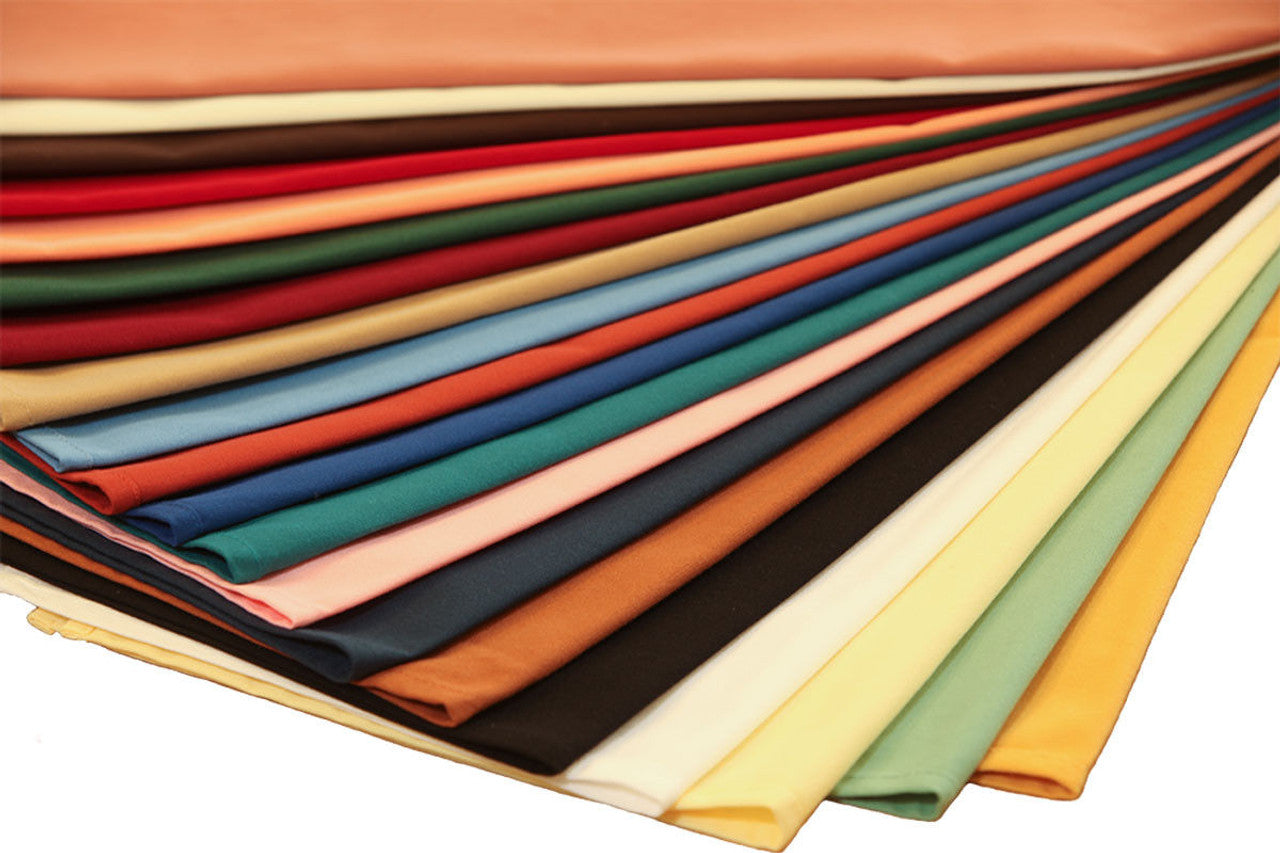 A vibrant fan display of Ganesh Mills Lapkins – Oversized Napkins in solid red, orange, yellow, green, blue, pink, brown, black, and cream polyester—ideal for events or bulk napkin needs.