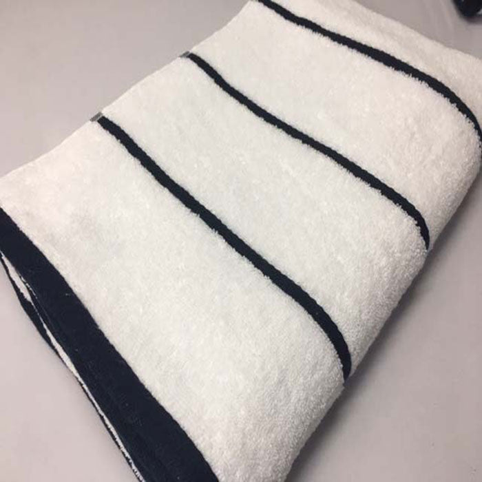 A folded Pro Towels Luxury Pool Towel with evenly spaced horizontal black stripes rests on a plain light surface, ideal for enhancing any poolside setting.