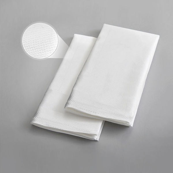 Two folded Ganesh Mills Bird Eye Napkins in white/black rest on a gray surface. A circular inset highlights the textured design, making these napkins ideal for restaurant bulk use.