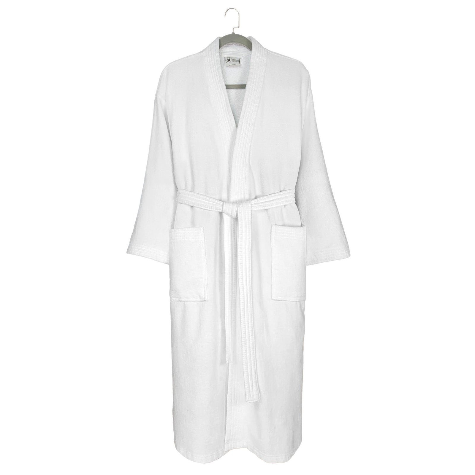 The Kimono - White Oxford Velour Bathrobe by Ganesh Mills, featuring long sleeves, two front pockets, and a matching waist belt, hangs on a hook against a plain background.