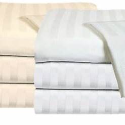 Two stacks of KSE Fitted Colored Sheets - Global Collection T-180 are shown in cream and white with a subtle striped pattern—ideal for anyone looking to buy wholesale bed sheets or bulk fitted sheets.