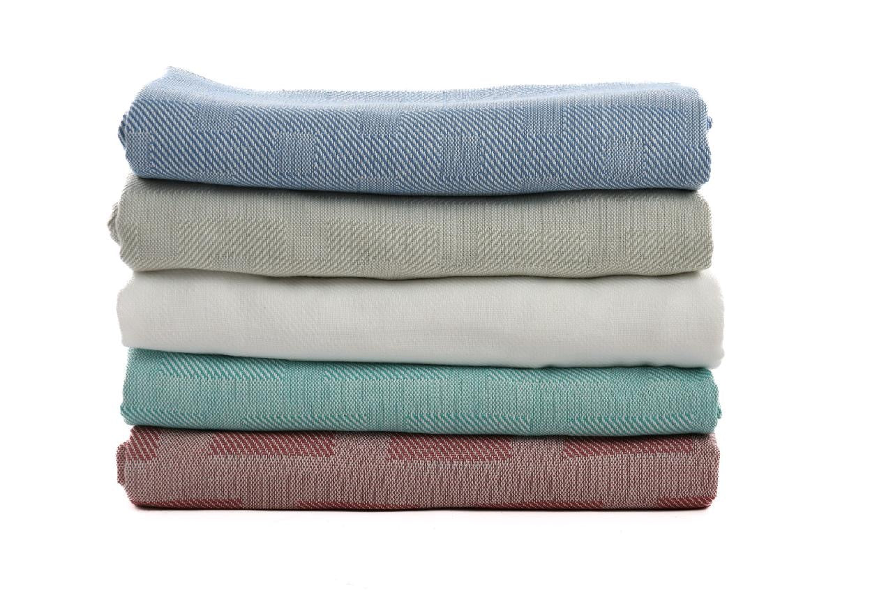 A stack of five KSE EverLast Spread Blankets in pastel blue, gray, white, green, and pink is neatly folded and arranged on a white background.