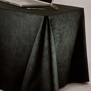 A rectangular table is covered with the 1Concier Conference Cloth Double-sided. A silver laptop, pen, and eyeglasses rest on top, while the image highlights the elegant draping fabric in the foreground.