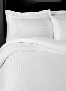 A neatly made bed with 1Concier's Flat Sheet T490 100% Cotton Sateen and matching pillowcases, featuring a subtle stripe and smooth finish. The high T-490 thread count adds an inviting touch, with a headboard partially visible in the background.