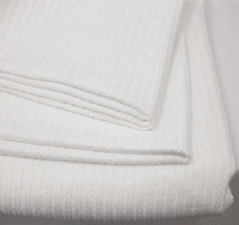 Close-up of folded, ribbed white towels stacked neatly—evoking the plush feel of the 1Concier Blanket Cotone 100% Cotton Blankets.