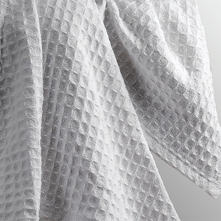 Close-up of the 1Concier Blanket Cape Cod, a white blanket with luxurious waffle weave texture, draped in soft folds and featuring a geometric grid pattern reminiscent of honeycomb.