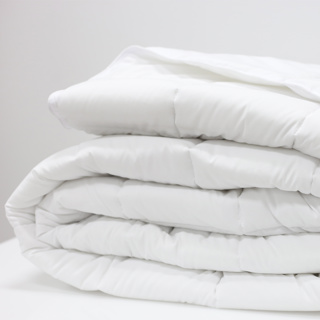 The 1Concier Sleep Blueprint Quilted Blanket, a plush white down alternative, is neatly folded on a white surface with a plain white background.