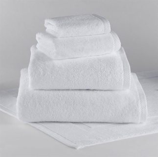 A neatly stacked set of four 1Concier Hand Towels, 100% cotton, each a different size from the Traditional Collection, sits on a white surface with another towel laid flat underneath for a sophisticated look.