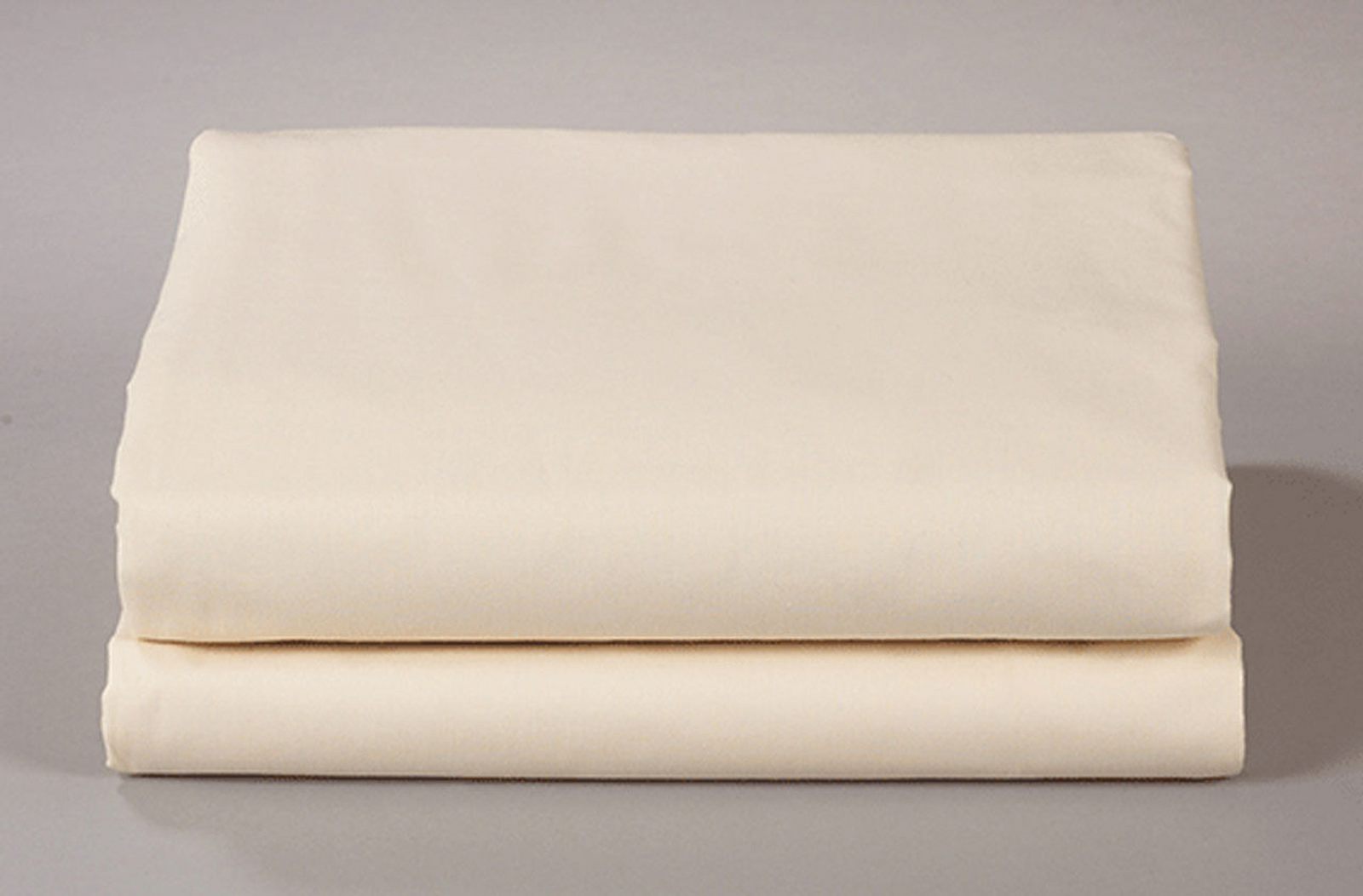 Two cream-colored Thomaston Mills Flat Sheets – 250 Thread Count are neatly folded and stacked against a plain, light grey background.
