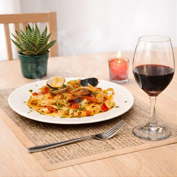 Natural fiber table placemat used in an elegant dining setup with plated meal, glassware, and decorative candle.