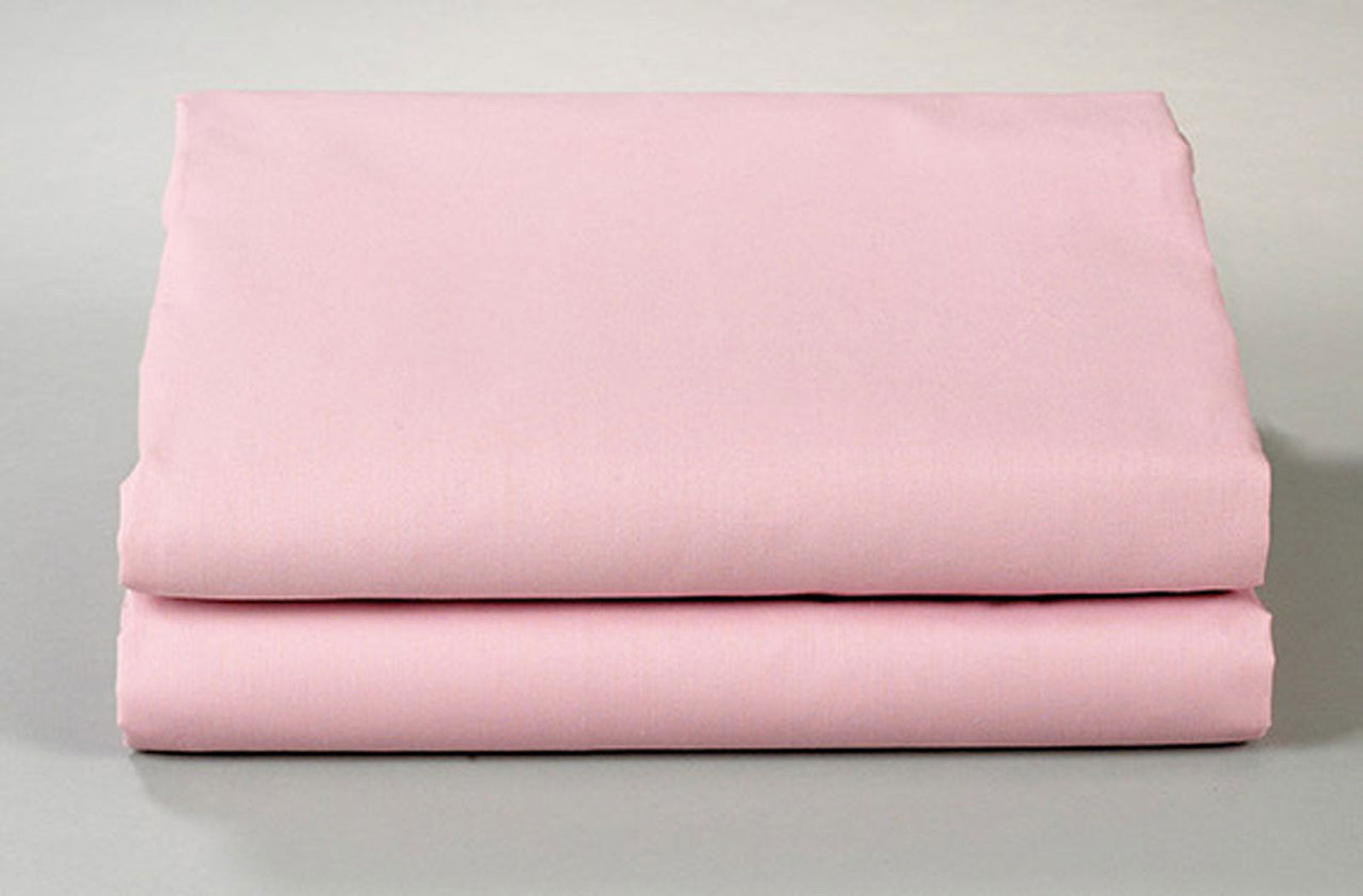 Two neatly folded Thomaston Mills Fitted Sheets - Single Pick Percale in light pink are stacked atop each other against a plain background, highlighting durable percale bed linens perfect for frequent use.