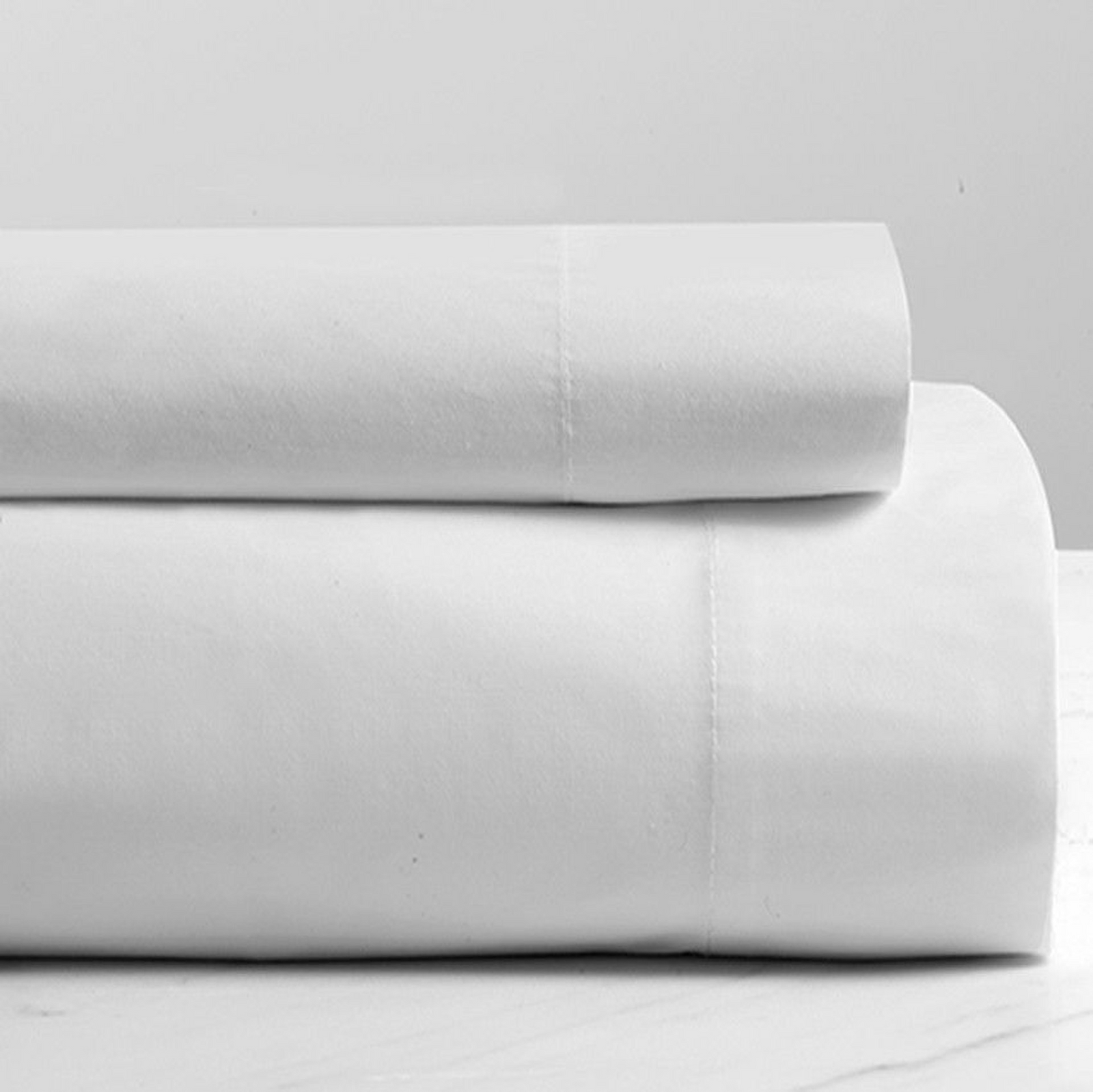 Two neatly folded 1Concier Flat Sheet Massage Table Soft wear bedding sheets are stacked on a white surface against a plain light background.