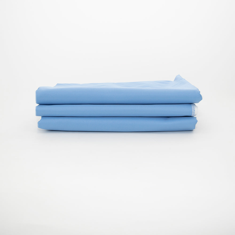 A stack of Calderon Textiles Slider T-180 Draw Sheets, crafted from cotton/polyester fabric in light blue, is neatly folded and arranged on a plain white background.