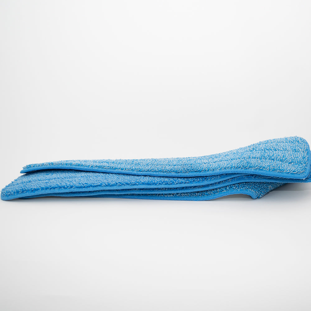 A blue Calderon Textiles Microfiber Mop Pad rests on a white surface with a plain white background, designed for lower laundering costs and superior cleaning performance.