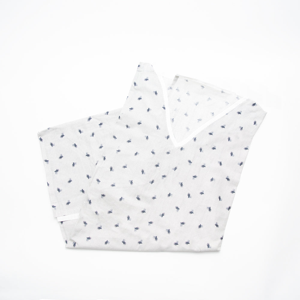 A Calderon Textiles V-Neck, Overlap Patient Gown for bariatric patients featuring a subtle blue leaf pattern is neatly folded on a white background.