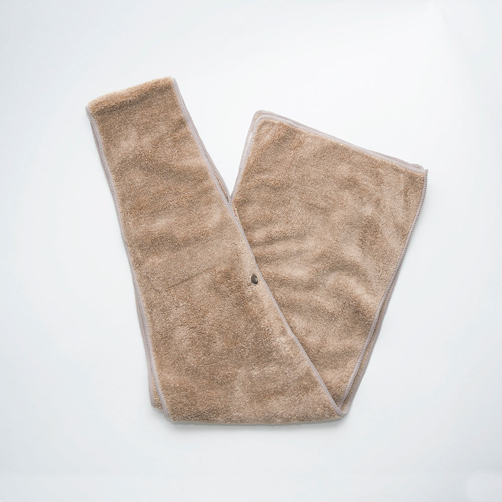 The Bib Microtex - Clothing Protector by Calderon Textiles is a beige, rectangular, soft terry cloth bib with rounded corners and a snap button, shown flat on a white background.